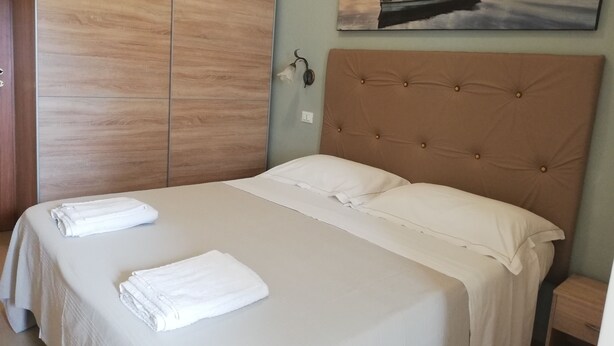 Un dormitorio con una cama grande, un armario de madera y un cuadro de un barco en el agua.