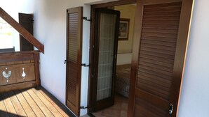 A wooden door with a glass panel, leading to a room with patterned carpet. - Le Cicogne (Rovereto)