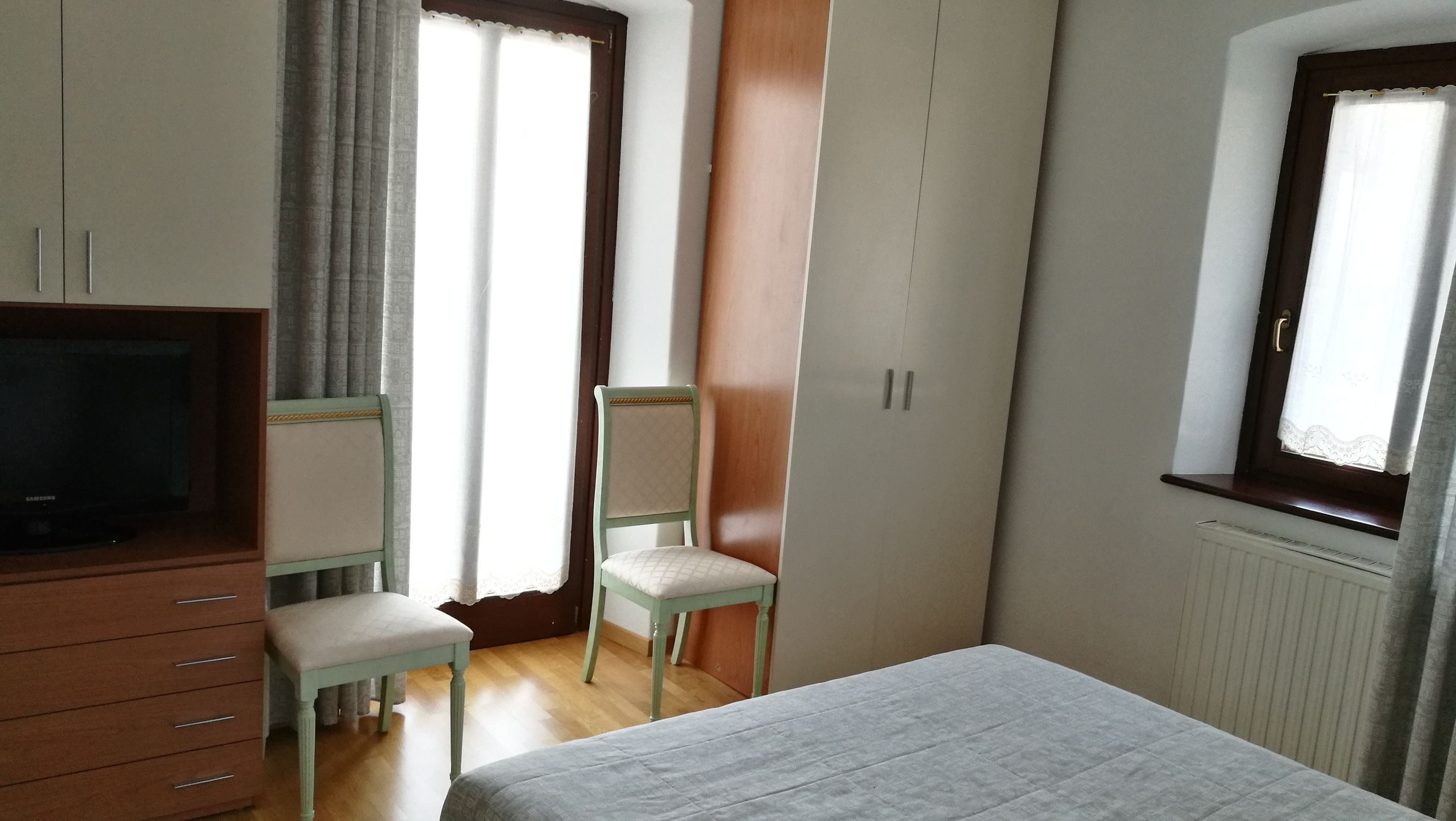 A bedroom with a bed, a TV, a wardrobe, and a chair.