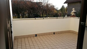 A tiled balcony with a view of trees and a statue. - Le Cicogne (Rovereto)