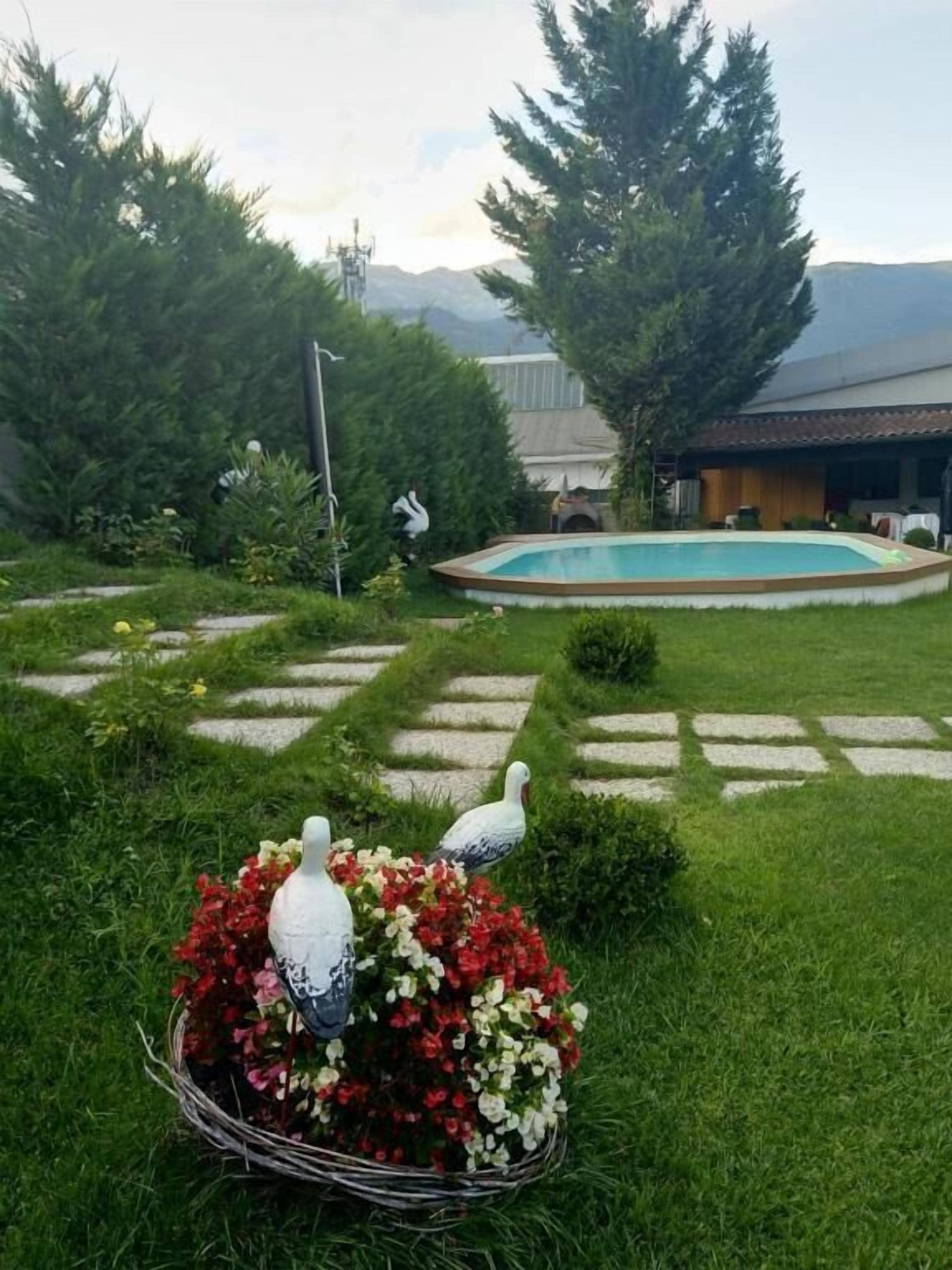 A garden with a swimming pool, a paved walkway, and a decorative bird sculpture.