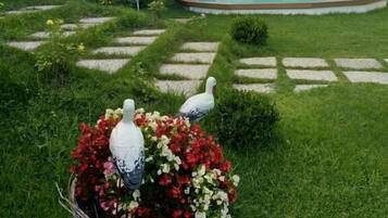 A garden with a swimming pool, a paved walkway, and a decorative bird sculpture.