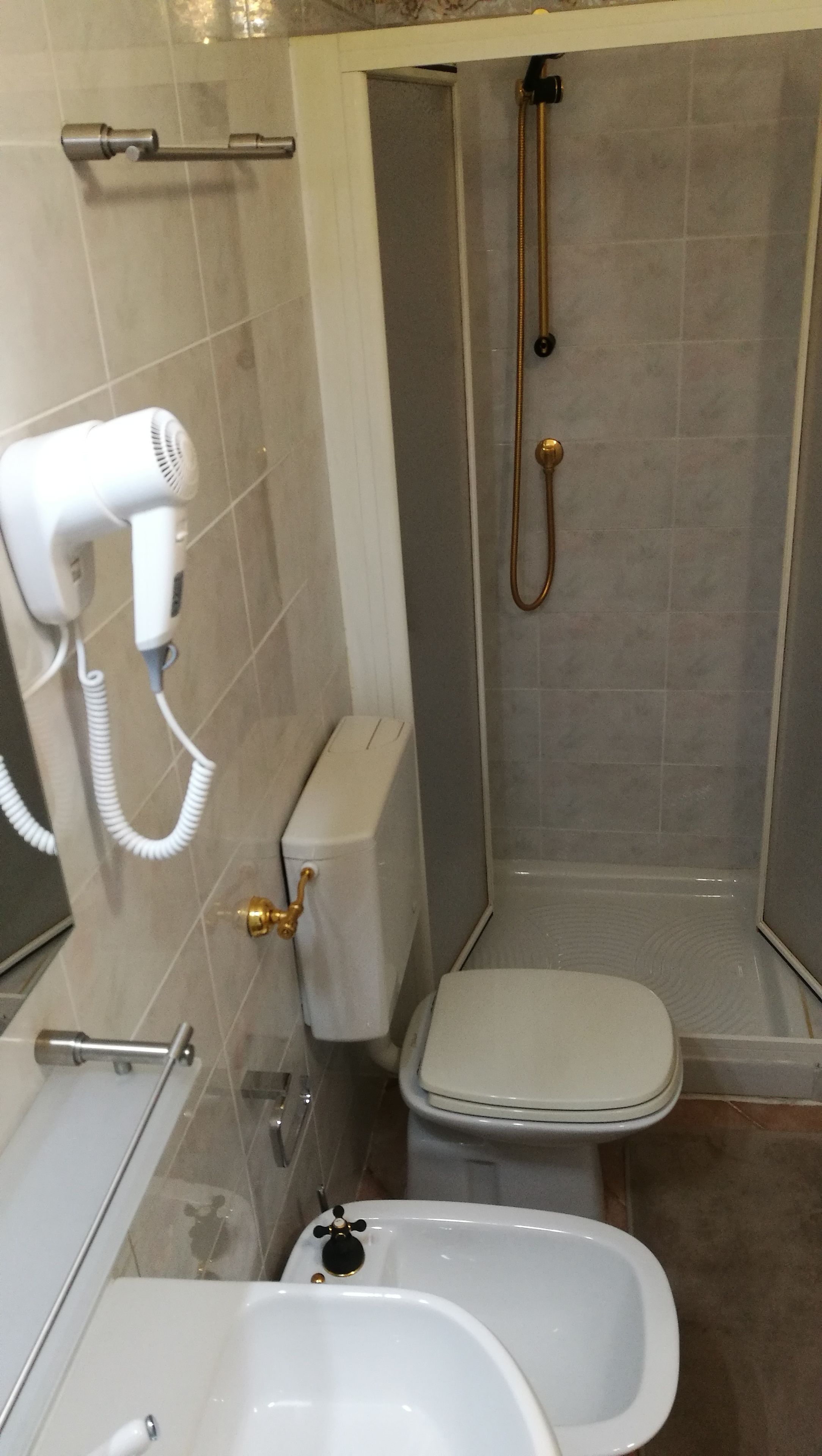 A bathroom with a toilet, bidet, and a hairdryer mounted on the wall.