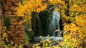 A stone bridge leading to a waterfall surrounded by autumn foliage. - Hotel La Gerencia (Checa)