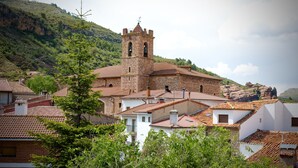 A historic stone church with a bell tower, surrounded by traditional buildings with terracotta roofs. - Hotel La Gerencia (Checa)
