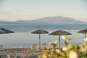 A beach with several sun umbrellas and lounge chairs.