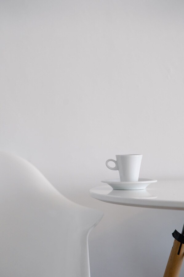A white table with a white cup and saucer on it.