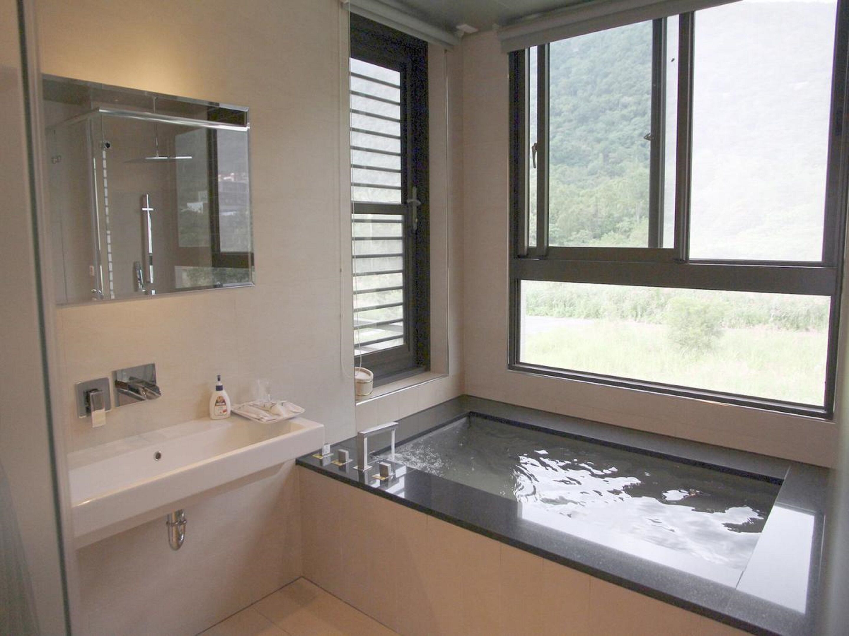 Une salle de bain moderne avec une grande fenêtre, une baignoire et un lavabo.