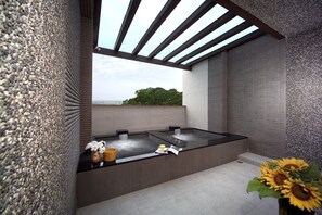 Un moderno espacio de spa con un amplio jacuzzi, un banco de madera y vistas al paisaje.