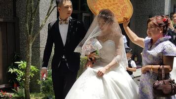 A wedding scene with a bride in a white dress and a groom in a black suit.