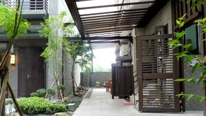 A narrow pathway leading to a traditional Japanese-style building with a wooden gate and a small garden area with rocks and plants. - Peace Area Hot Spring Hotel (Jiaoxi)