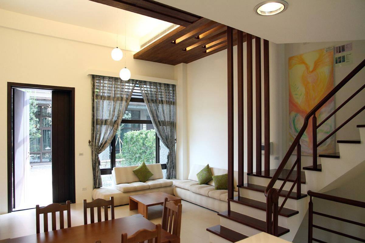 Un salon moderne comprenant un canapé, une table à manger et des chaises, un escalier et une grande fenêtre avec des rideaux.