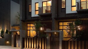 A modern building with multiple windows, a gated entrance, and a small tree in front. - Peace Area Hot Spring Hotel (Jiaoxi)