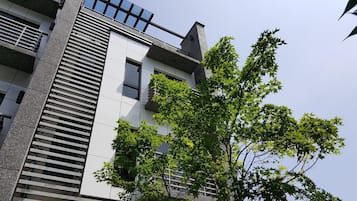 A modern building with a sloped roof, large windows, and a tree in front.