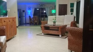 A living room with a sofa, a coffee table, and a cabinet. There is a dining area with chairs and a table in the background. - 4 Bedroom House & Private Pool Pattaya (Pattaya)