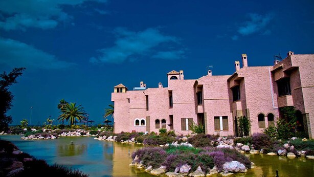 A pink building with a pool and palm trees. - Bungalows Bahia Sur (San Fernando)
