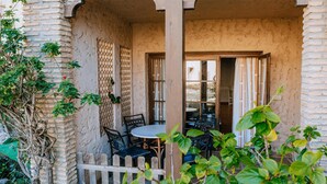 A covered outdoor seating area with a table and chairs, a wooden fence, and a brick wall. - Bungalows Bahia Sur (San Fernando)