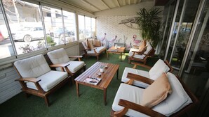 A sunlit indoor seating area with wooden furniture and a green artificial turf floor. - Grand Nora Hotel (Ankara)