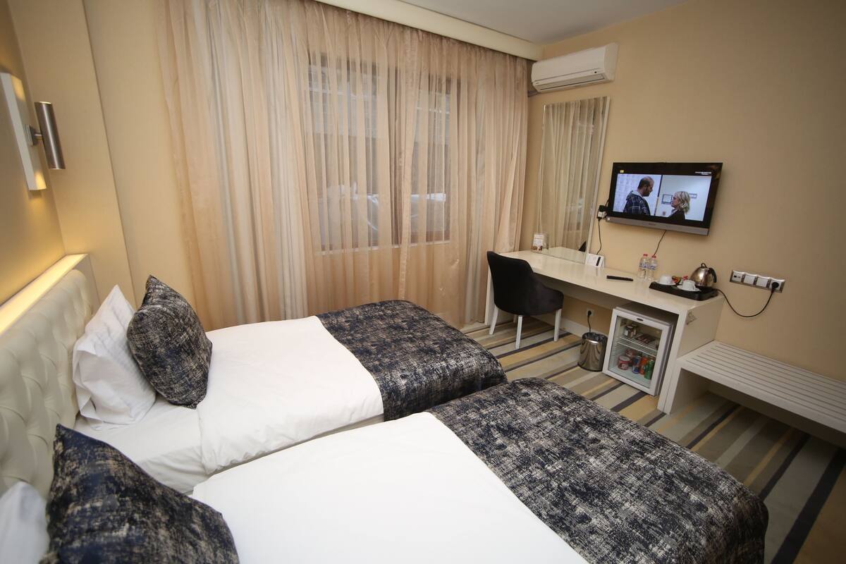 Une chambre d’hôtel avec deux lits, un bureau, une télévision et un minibar.