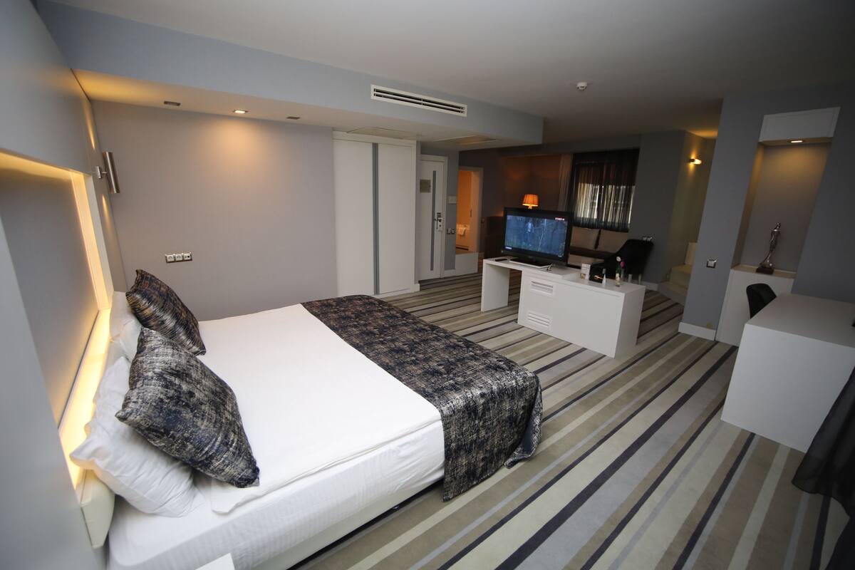 Une chambre d’hôtel moderne, dotée d’un grand lit, d’un bureau et d’une télévision.