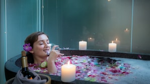 Una persona en una bañera con velas y flores.