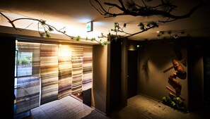 A hallway with striped curtains, a ceiling with hanging branches, and a wall-mounted sculpture. - Kyoto Art Stay Nishijin Sutematsu (Kyoto)