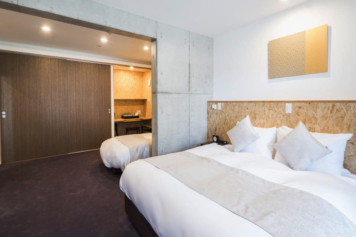 Habitación de hotel con dos camas, cabecero de madera, un escritorio pequeño y un armario.