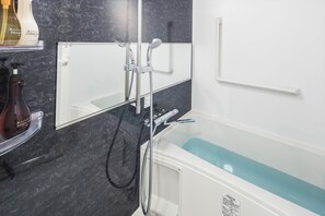 A modern bathroom with a bathtub, a shower, and a mirror. - Kyoto Art Stay Nishijin Sutematsu (Kyoto)