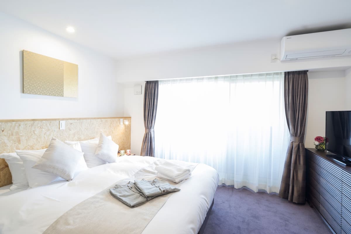 Habitación de hotel con una cama grande, televisión de pantalla plana, aire acondicionado y una ventana con cortinas.