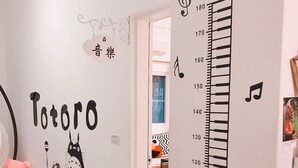 Een kinderkamer met een groeimeter op de muur, een pluchen beer en een Totoro muurstickers.