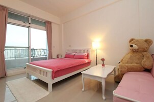 A bedroom with a bed, bedside table, and a large teddy bear.