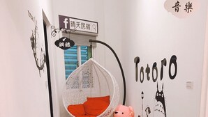 Een hal met een hangstoel, een teddybeer en een Totoro muurschildering.