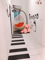 A hallway with a hanging chair, a teddy bear, and a Totoro mural on the wall.