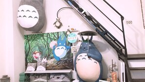 Een kamer met een groot muurdecoratie van tekenfilmfiguren, een trap en een verzameling pluchen knuffels.