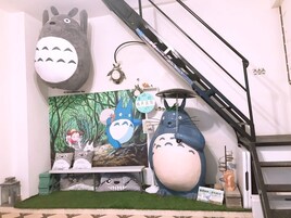 A room with a large mural of animated characters, a staircase, and a display of plush toys.