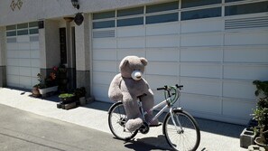 A friendly bear enjoys a bike ride in front of a charming garage.