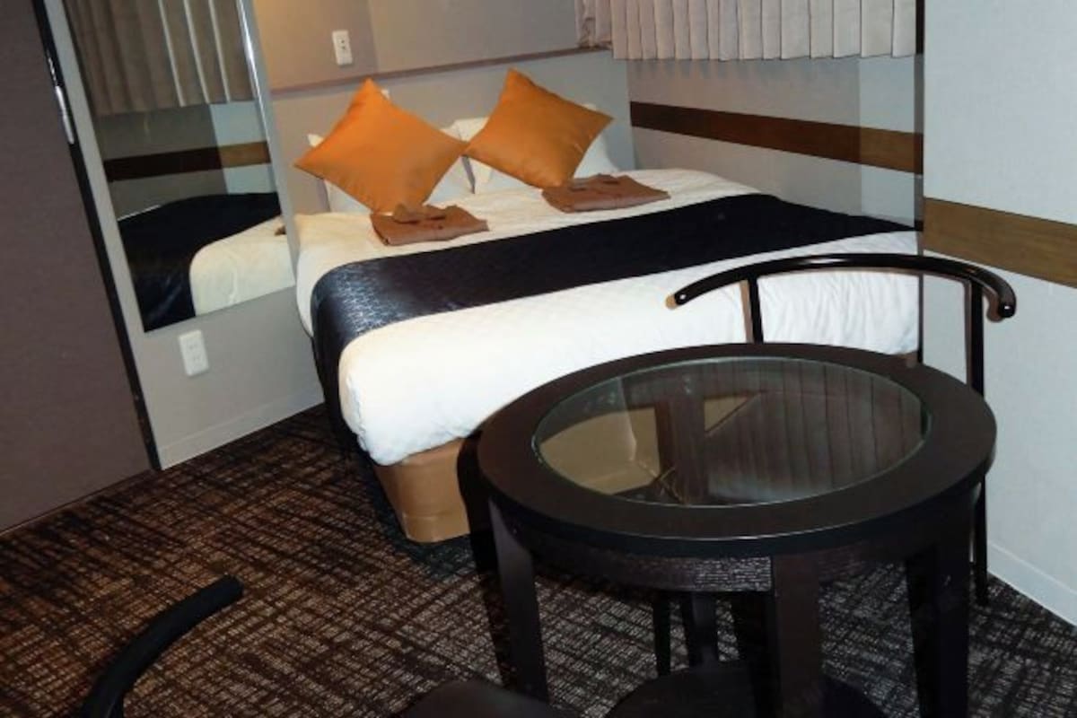 A hotel room with a bed, a round glass table, and a chair.