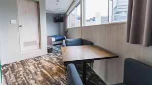 A compact room with a bed, a small table, and a window with curtains. - Hotel S-Presso North (Osaka)