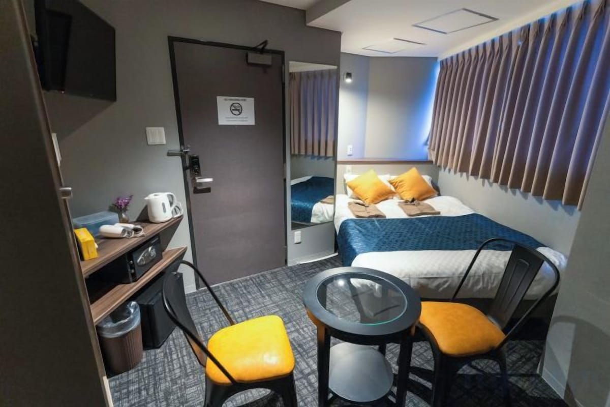 Una habitación de hotel con una cama, un escritorio con una silla, una mesita y un espejo.