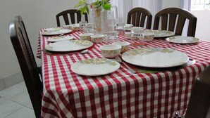 A dining table set with plates, bowls, and a pitcher, covered with a red and white checkered tablecloth. - Casa Mia (Guwahati)
