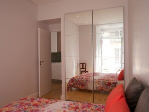 Ein Schlafzimmer mit einem Spiegelkleiderschrank, einem Bett mit floralem Bettzeug und einem Sessel.