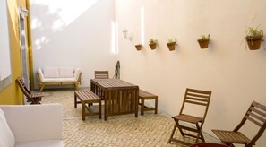 A patio area with a wooden table and chairs, a white sofa, and potted plants on the wall. - Cacilhas Guest Apartments (Almada)