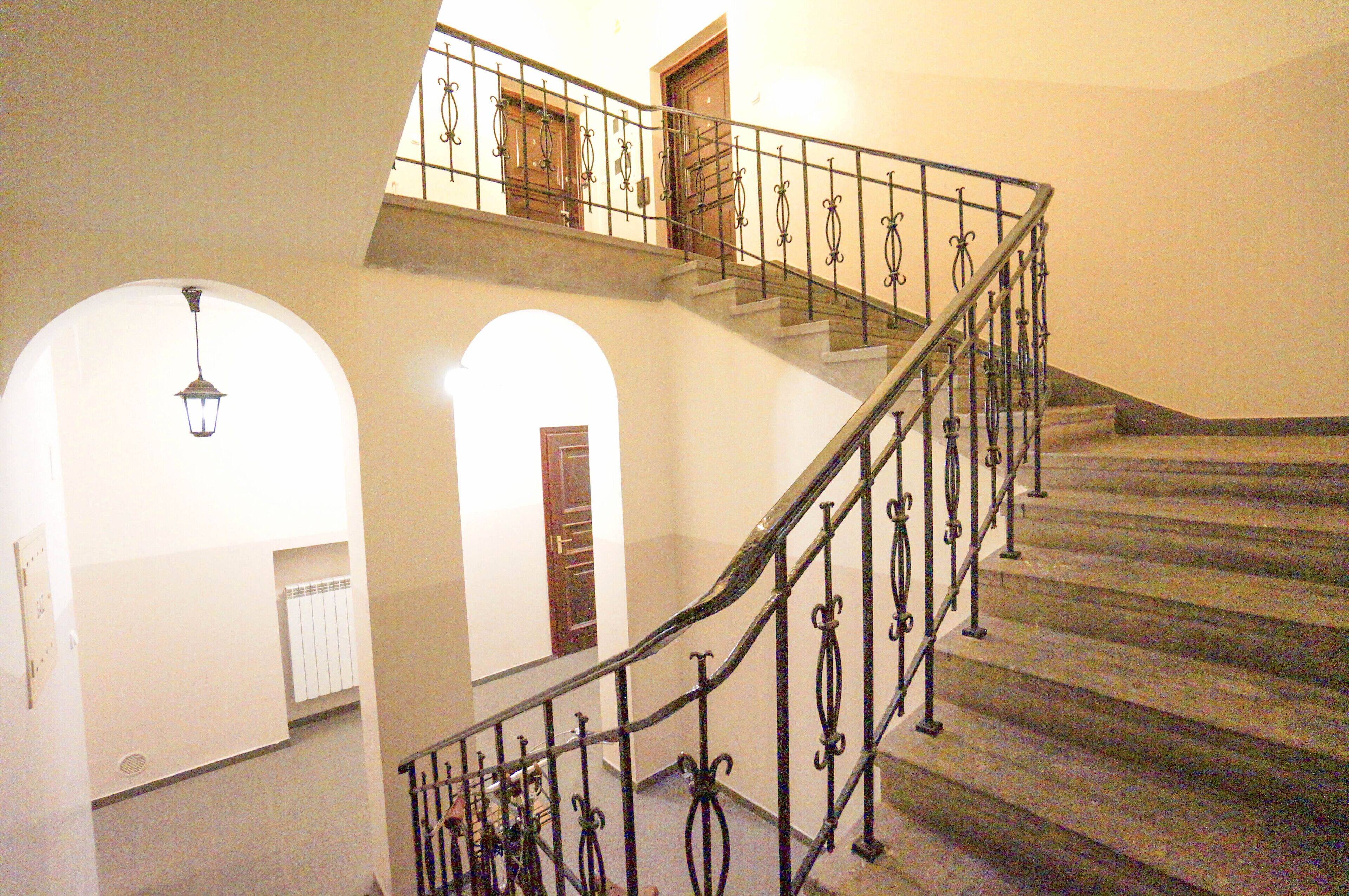 A staircase with ornate metal railings and a wooden door at the top.