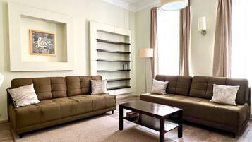 A living room with two sofas, a coffee table, a bookshelf, and a wall-mounted lamp.