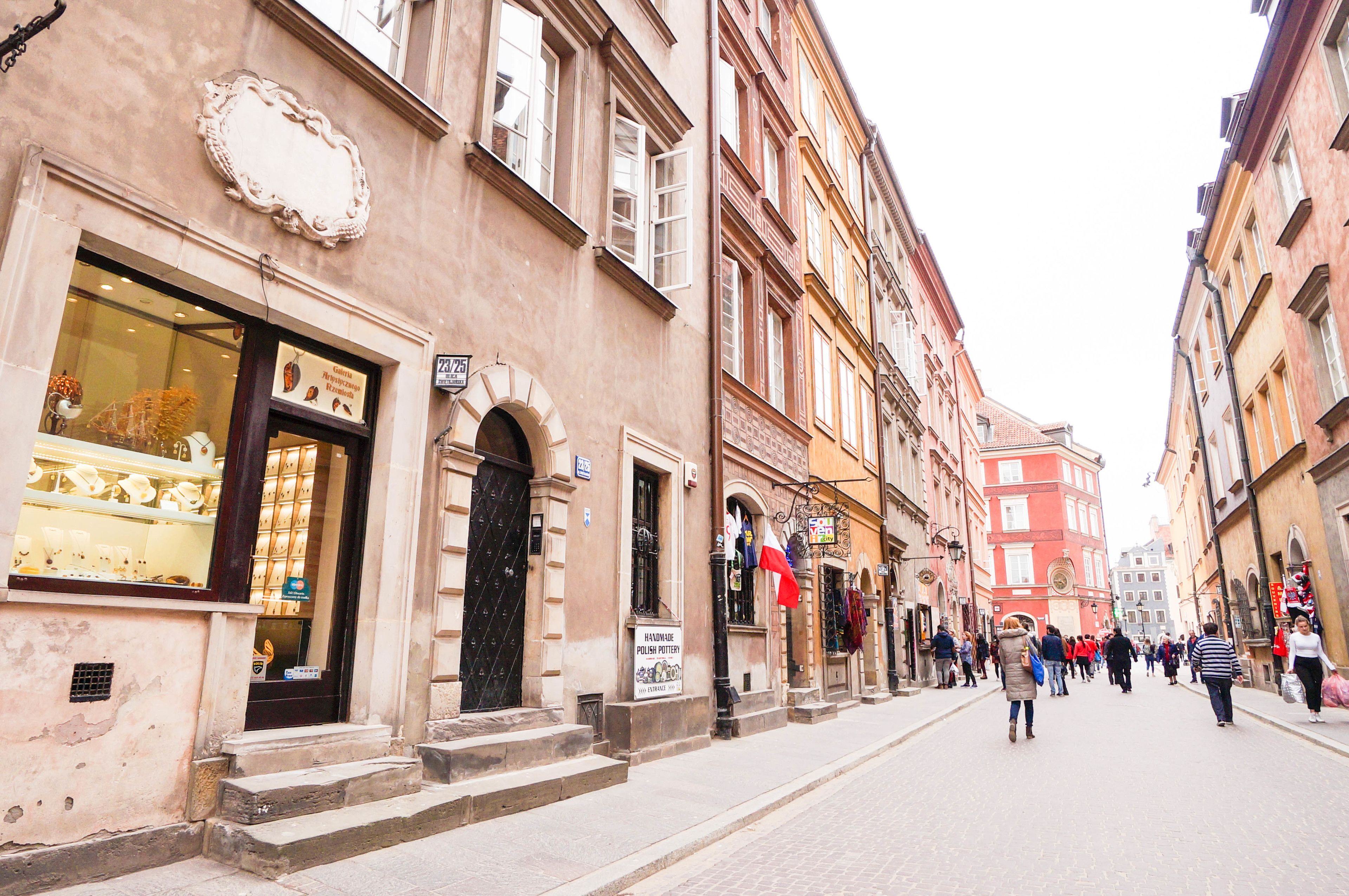 Eine Straße mit historischen Gebäuden, einem Laden mit Schaufenstern und Fußgängern.