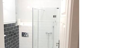 Ein kleines, weißes Badezimmer mit einer Duschkabine, einer Toilette und einem Waschbecken.