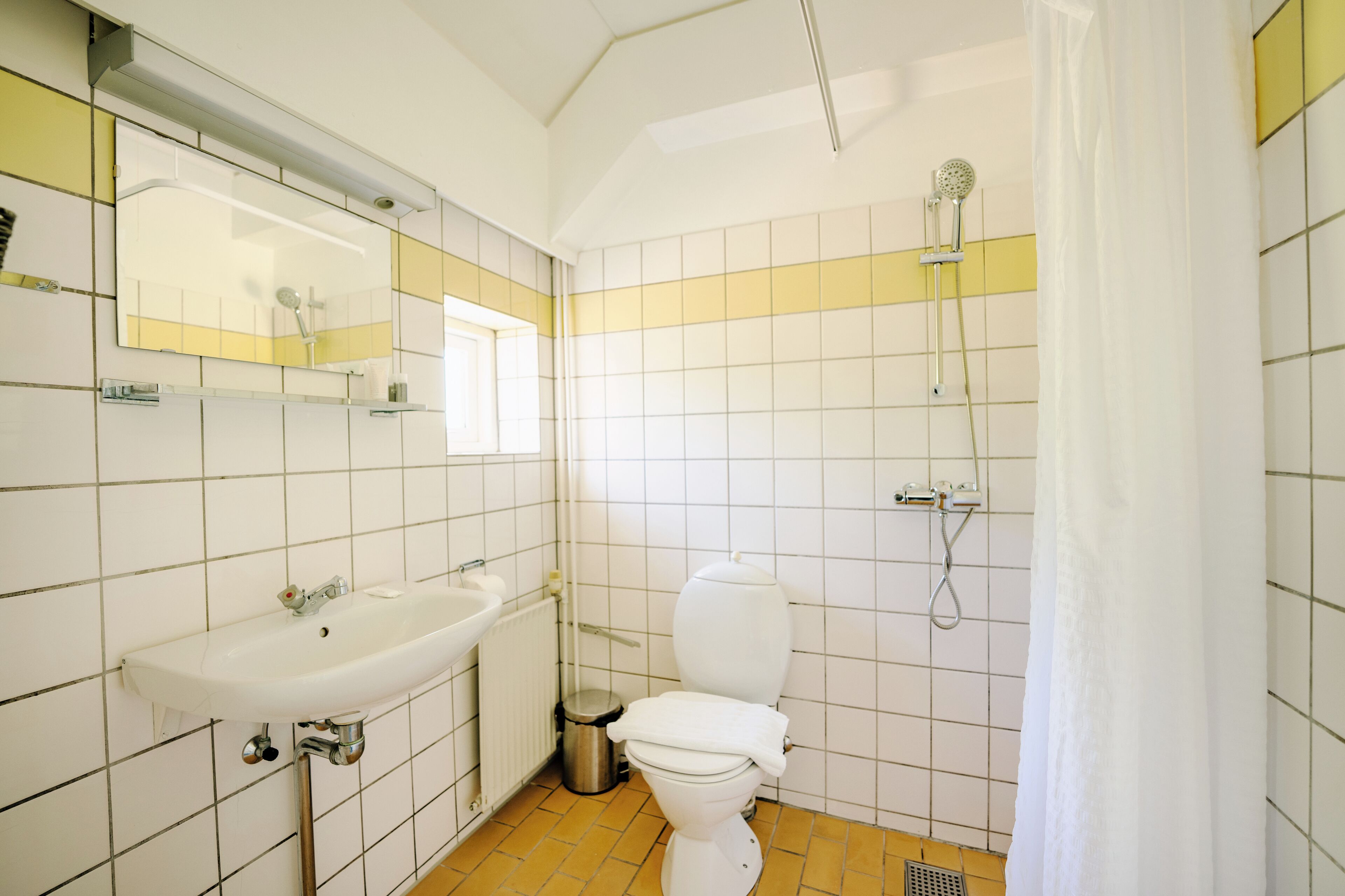 A bathroom with a white sink, toilet, and shower.