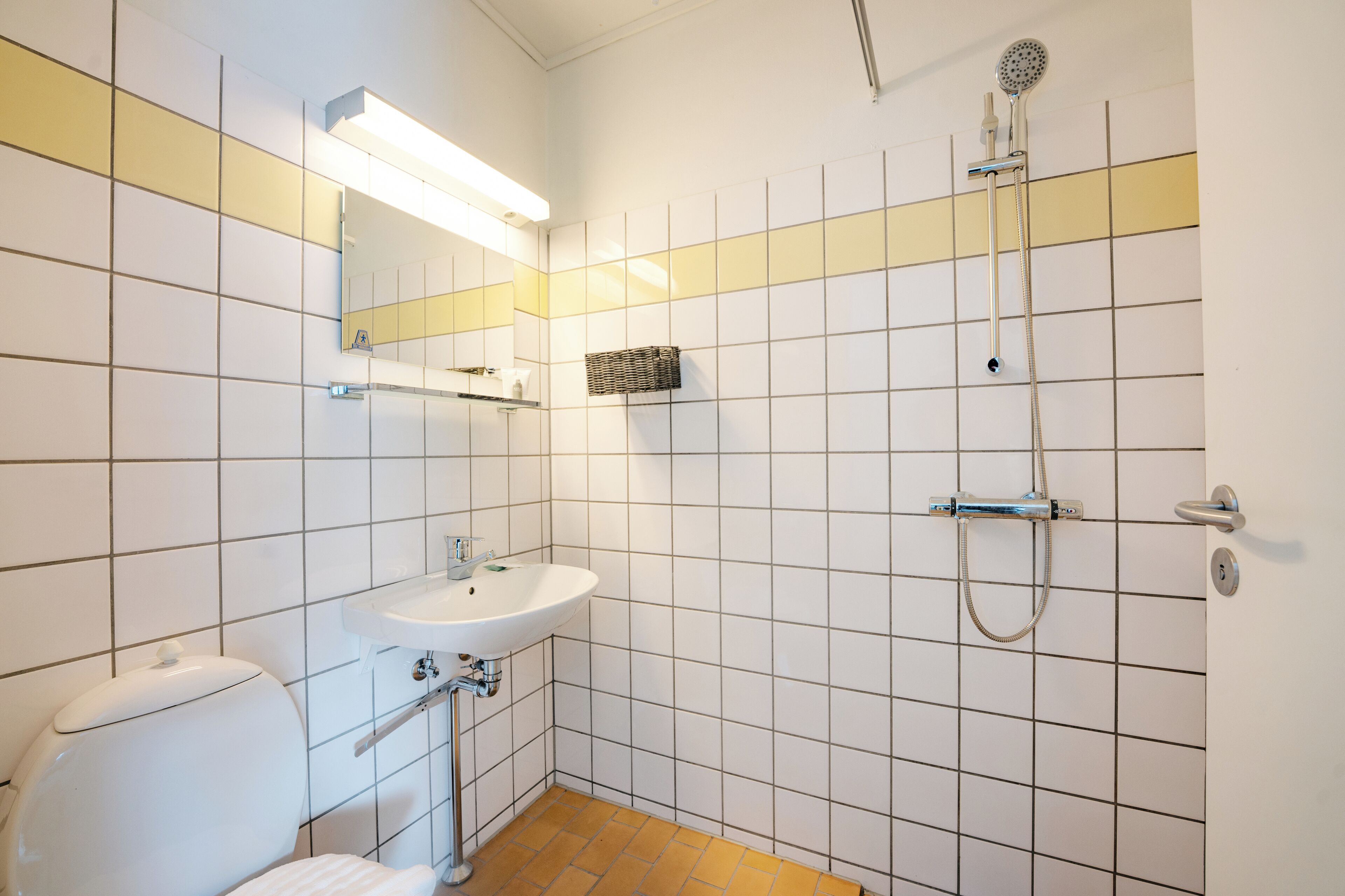 Ein Badezimmer mit Toilette, Waschbecken, Spiegel und Dusche.