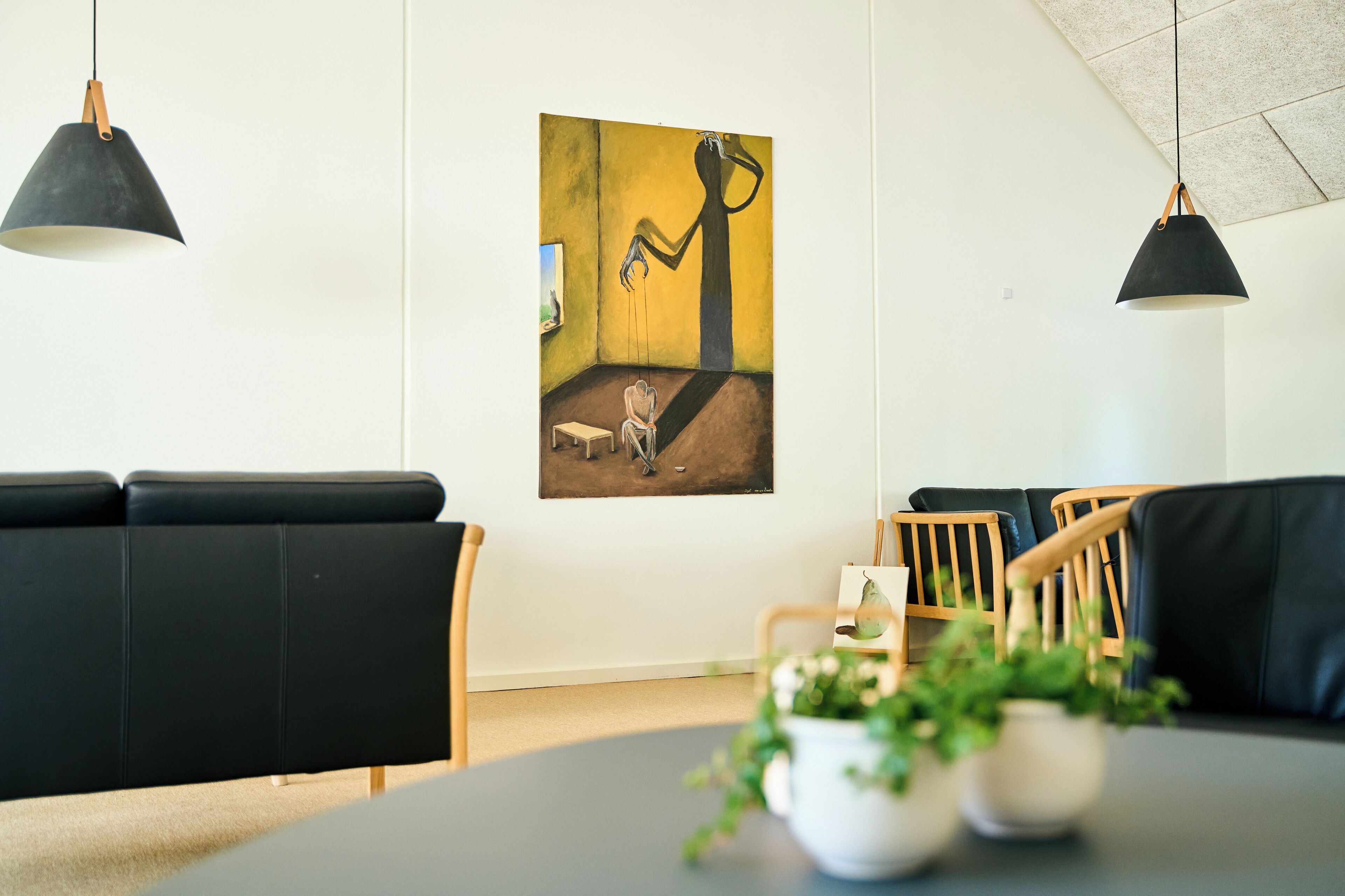 Un soggiorno moderno con divani in pelle nera, un tavolino con una pianta in vaso e un quadro appeso al muro.