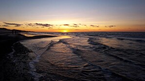 Una playa al atardecer, con olas lamiendo suavemente la orilla.